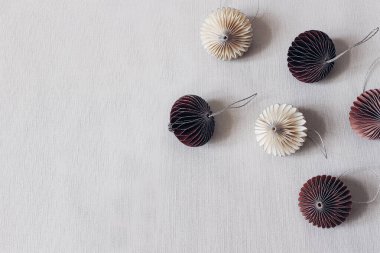 Noel stili borsa kompozisyonu. Gri masa örtüsü arkaplanındaki dekoratif beyaz ve kıpkırmızı Noel süsleri. Düz yerde, üst tarafta. Kış şenlik düzeni, boş kopya alanı.