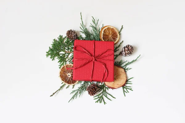 크리스마스 축제는 주식 이미지 구성을 스타일링 했다. 붉은 색 포장된 선물 상자, 사이프러스 나뭇가지, 말린 애플, 오렌지 열매, 솔방울 이 흰 테이블 배경에 분리되어 있다. 겨울 방학. 위에서 내려다 본 평평 한 모습. — 스톡 사진