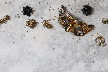 Yeni yıl kompozisyonu, karnaval maskeli web afişi, siyah ve altın konfeti yıldızları. Parti dekorasyonu, kutlama konsepti. Düz yerde, üst tarafta. Grunge beton arka planı. Boş kopyalama alanı.