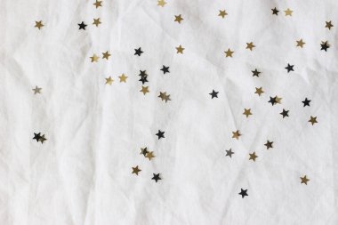Noel, yeni yıl kompozisyonu. Beyaz keten masa örtüsü üzerinde dekoratif altın ve siyah konfeti yıldızları. Kutlama, doğum günü partisi konsepti. Düz yerde, üst tarafta. Boş kopyalama alanı.