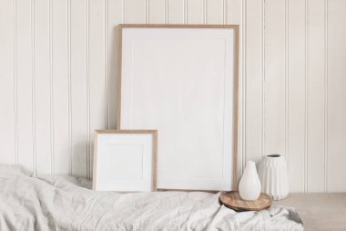 Portre ve kare boş ahşap çerçeve maketleri keten kumaş ve modern seramik vazolarla. Beyaz boncuklu duvar paneli arka plan. İskandinav iç mimarisi, ev tasarımı. Sanat konsepti.
