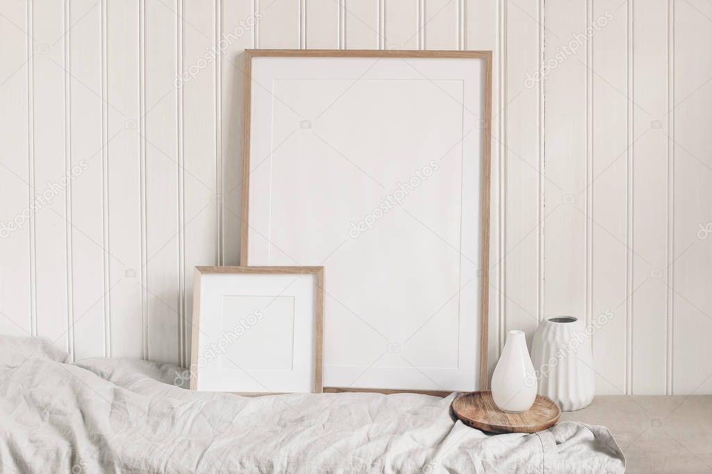 Portrait and square empty wooden frame mockups with linen cloth and modern ceramic vases. White beadboard wainscot wall paneling background. Scandinavian interior, home design. Art concept.