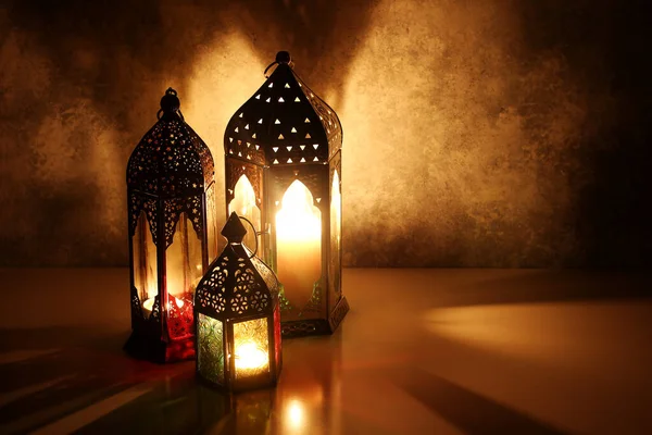 Lanternas árabes ornamentais com velas acesas na mesa brilhando à noite. Cartão festivo, convite para o mês sagrado muçulmano Ramadã Kareem. Iftar jantar fundo com brilho dourado . — Fotografia de Stock