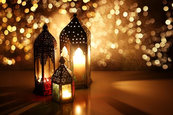 Ornamental Arabic lanterns with glittering bokeh lights. Burning candles on table glowing at night. Festive greeting card, invitation for Muslim holiday Ramadan Kareem. Golden Iftar background. — Stock Photo, Image