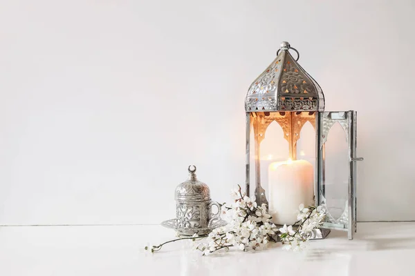 Silber dekorative Tasse Tee, weiße Blumen, Pflaumenbaumblüten und glühende marokkanische Laterne auf dem Tischhintergrund. Iftar-Dinner. Ramadan Kareem Grußkarte, Einladung. Muslimischer Feiertag Eid ul Fitr. — Stockfoto