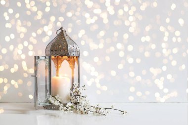 Beyaz çiçekler, erik ağacı çiçekleri ve arka planda altın bokeh ışıklarıyla parlayan gümüş renkli Fas feneri. Havan topu yemeği. Ramazan Kareem tebrik kartı, davet.