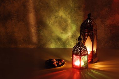 Süslü Arapça fenerler ve hurma meyveli tabaklar. Geceleri masalarda yanan mumlar. Kutlama kartı, Müslüman kutsal ayı için davetiye Ramazan Kareem. Havan topu yemek arkaplanı.