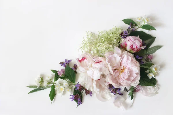 Spring, summer botanical floral composition, decorative corner. Pink peony flowers, sage, elderflower herbs and blooming philadalphus branches isolated on white table background. Flat lay, top view. — Stock Photo, Image