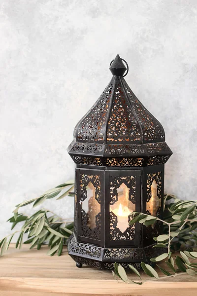 Dark decorative Moroccan lantern. Green olive leaves, branches on old wooden table. Selective focus, shabby wall background. Greeting card for Muslim holiday Ramadan Kareem. Still life, vertical. — Stock Photo, Image