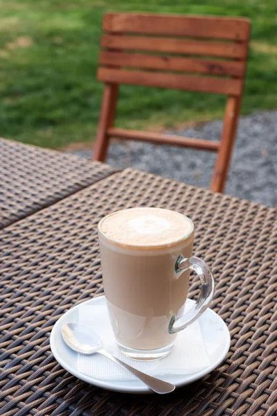 Xícara de café arte latte quente em mesa de madeira de vime no café ao ar livre . — Fotografia de Stock