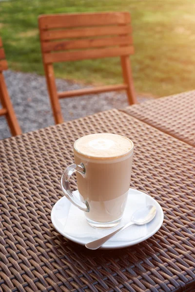 Xícara de café arte latte quente em mesa de madeira de vime no café ao ar livre . — Fotografia de Stock