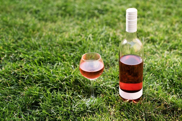 Egy üveg és üveg vörös vagy rose bor. őszi kertben zöld fűben. Betakarítás ideje, piknik, fest téma. — Stock Fotó