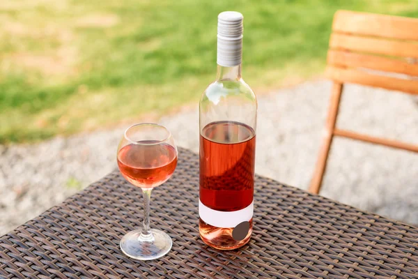 One glass and bottle of red or rose wine in autumn vineyard on wooden wicker table. Harvest time, picnic, fest theme. — Stock Photo, Image