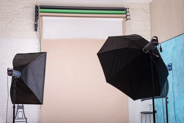 Empty photo studio with lighting equipment and paper background ready for photoshoot.