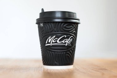 Kiev, Ukrayna: 06 Kasım 2019: McDonald 's Coffee in black cup Mccafe üzerinde açık arkaplanlı ahşap masa.
