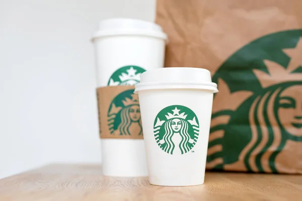 Kiev, ukraine: 06. November 2019: Starbucks Kaffee zum Mitnehmen Tassen mit Papiertüte auf Holztisch. amerikanisches globales Kaffee- und Kaffeehausunternehmen, gegründet in Seattle, wa. USA, 1971 — Stockfoto