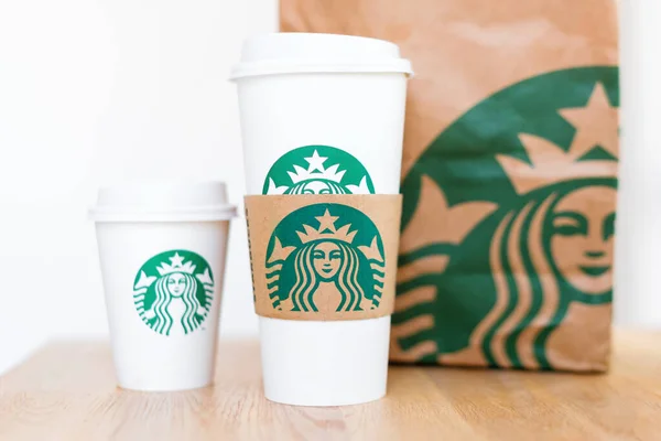 Kiev, ukraine: 06. November 2019: Starbucks Kaffee zum Mitnehmen Tassen mit Papiertüte auf Holztisch. amerikanisches globales Kaffee- und Kaffeehausunternehmen, gegründet in Seattle, wa. USA, 1971 — Stockfoto