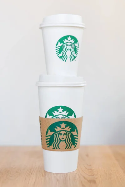 KIEV, UCRANIA: 06 de noviembre de 2019: Starbucks Café llevar vasos de papel con logotipo en la mesa de madera. American global coffee and coffeehouse company, fundada en Seattle, Wa. Estados Unidos, en 1971 —  Fotos de Stock
