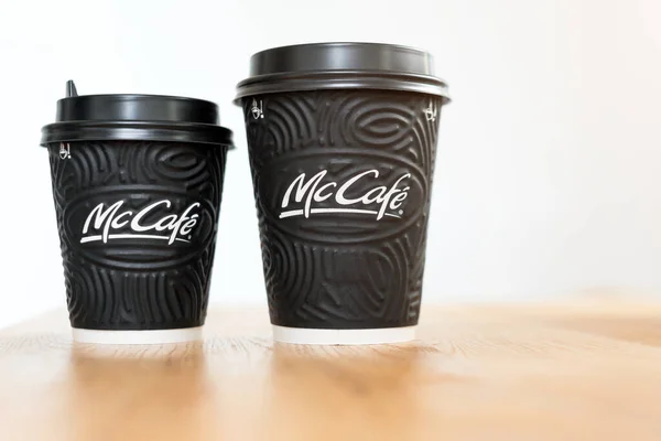 Kiev, Oekraïne: 06 november 2019: Mcdonald 's koffie in zwarte kopjes Mccafe op houten tafel op lichte achtergrond. — Stockfoto