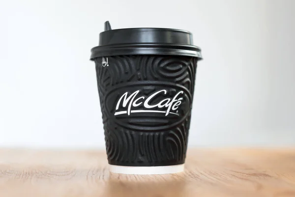 KIEV, UCRANIA: 06 de noviembre de 2019: Café McDonald 's en taza negra McCafé sobre mesa de madera sobre fondo claro . — Foto de Stock