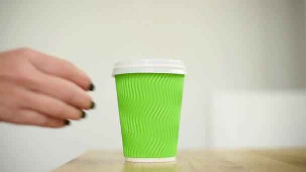 Close-up female takes a coffee or tea and puts it back, focus on paper cup. Hand taking paper cup of coffee, hot beverage for breakfast, takeaway service — Stock Video
