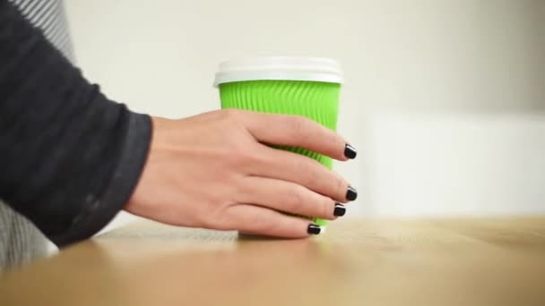 Fêmea close-up toma um café ou chá, foco em xícara de papel. Mão tomando xícara de papel de café, bebida quente para o café da manhã, serviço takeaway — Vídeo de Stock