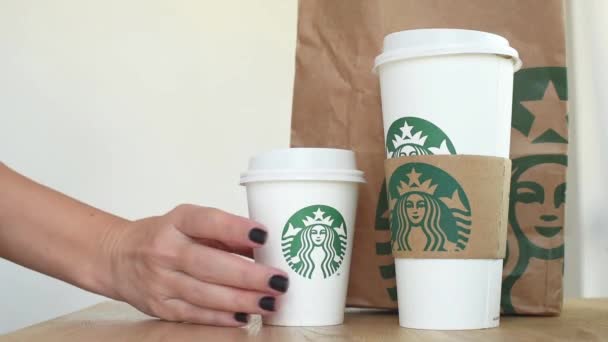 KIEV, Ucrania. Noviembre 06, 2019: Close-up female takes Starbucks Coffee and puts it back, focus on paper cup. Mano tomando taza de papel de café, servicio de comida para llevar — Vídeo de stock