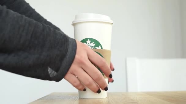 KIEV, Ucrania. Noviembre 06, 2019: Close-up female takes Starbucks Coffee and puts it back, focus on paper cup. Mano tomando taza de papel de café, servicio de comida para llevar — Vídeo de stock