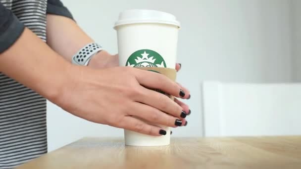 KIEV, Ucrania. Noviembre 06, 2019: Close-up female takes Starbucks Coffee and puts it back, focus on paper cup. Mano tomando taza de papel de café, servicio de comida para llevar — Vídeos de Stock