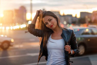 Arka planda odağını kaybetmiş şehir ışıklarıyla sokakta yürüyen güzel genç bir kadın. Hippi kız gece hayatının tadını çıkarıyor. Deri ceketli moda kızı. Sokakta şehrin ışıklarıyla bekliyor.