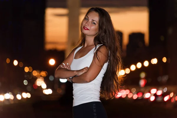 Bella giovane donna che cammina per strada con luci della città sfocate sullo sfondo. Ragazza hipster godendo la vita notturna, ragazza di moda in piedi sulla strada con illuminazione della città — Foto Stock