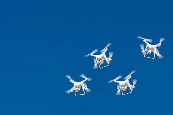 Tuziny dronów roją się na niebieskim niebie. Czworogłowe drony z cyfrową kamerą w powietrzu nad miastem. Nowa technologia fotografowania i filmowania zdjęć lotniczych. Copyspace dla tekstu — Zdjęcie stockowe