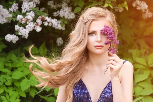 Retrato de jovem bela mulher loira posando entre floração lilás. Foto de moda ao ar livre de uma jovem rodeada de flores. Flor de primavera — Fotografia de Stock