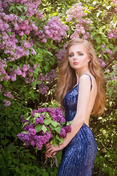 Porträt einer jungen schönen blonden Frau, die inmitten blühenden Flieders posiert. Outdoor-Modefoto einer jungen Frau, umgeben von Blumen. Frühlingsblüte — Stockfoto