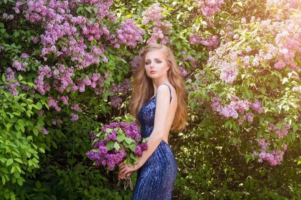 Retrato de jovem bela mulher loira posando entre floração lilás. Foto de moda ao ar livre de uma jovem rodeada de flores. Flor de primavera — Fotografia de Stock