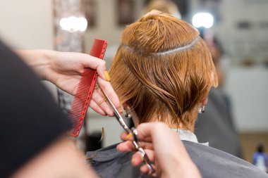 Yeni saç kesimi yaptıran bir kadın. Kuaförde saç kesen kadın kuaför. Kuaför, el ele tutuşup saç, tarak ve makas arasına girer..