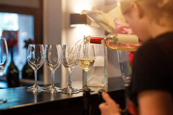 Bartender girl pours white wine into glasses. Restaurant bar, wine party — ストック写真