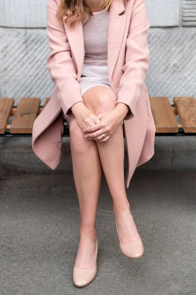 Woman sitting cross legged wearing pink clothes and beige flats — ストック写真