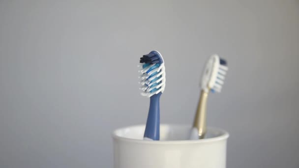 Woman hand taking plastic toothbrush from glass in bathroom and putting it back — Stock Video