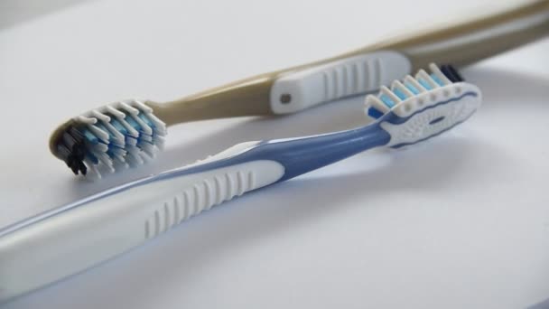 Dos cepillos de dientes de plástico girando de cerca sobre fondo gris — Vídeo de stock