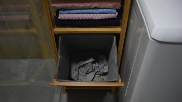 Des vêtements sales remplissent un panier à linge dans la salle de bain. Jeter des vêtements sales au panier . — Video