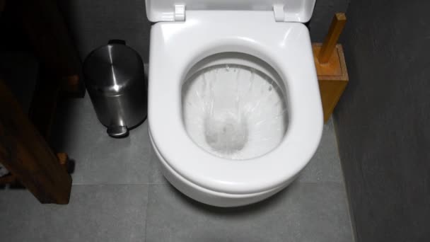 Toilet dibilas. Pemandangan tertutup air yang memerah ke dalam toilet di kamar mandi. Air mengalir ke toilet. — Stok Video