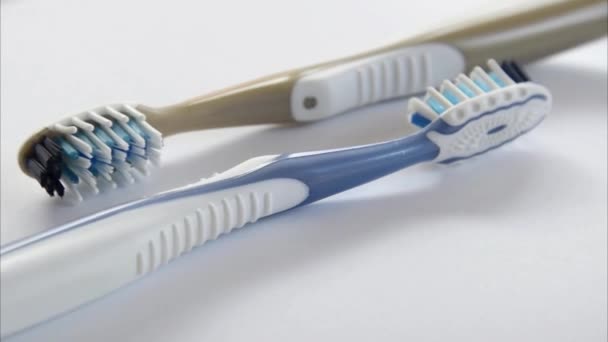 Two plastic toothbrushes rotating closeup on grey background — Stock Video