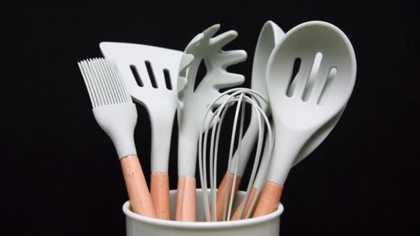 Rotation of silicone or rubber kitchen utensils on black background. Tools for cooking — Stock Video