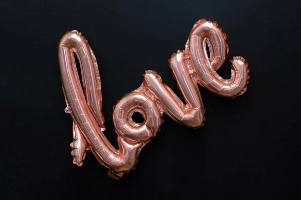 Palabra de amor del globo inflable rosado sobre fondo negro. El concepto de romance, el Día de San Valentín. Amor rosa globo de lámina de oro aislado en negro — Foto de Stock