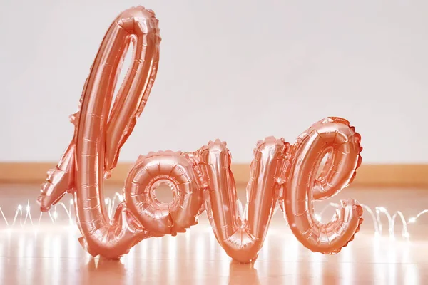Balon foliowy z różowego złota w formie słowa Miłość z lekką girlandą. Szczęśliwych Walentynek. Słowa listy miłosne z nadmuchiwanych balonów z bokeh — Zdjęcie stockowe