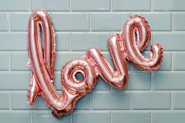 Kärlek ord från rosa uppblåsbar ballong på mynta kakel vägg bakgrund. Begreppet romantik, Alla hjärtans dag. Kärlek steg guld folie ballong — Stockfoto
