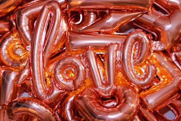 Liebeswort aus rosa aufblasbarem Ballon, der auf anderen Luftballons liegt. Das Konzept der Romantik, Valentinstag. Liebe Rose Gold Folie Ballon — Stockfoto