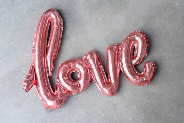 Gri beton arka planda pembe şişme balondan aşk sözü. Romantizm konsepti, Sevgililer Günü. Aşk gülü altın folyo balonu — Stok fotoğraf