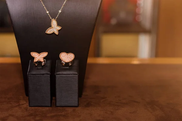 Naszyjnik i pierścionki wykonane ze złota z diamentami na stoisku w butiku modowej biżuterii. Czarny stojak szyi z luksusowej biżuterii, akcesoria kobiet w witrynie sklepu. — Zdjęcie stockowe